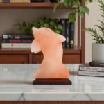 Handcrafted dolphin shape USB lamp carved from pink Himalayan salt with sculpted fins mounted on a dark wooden base
