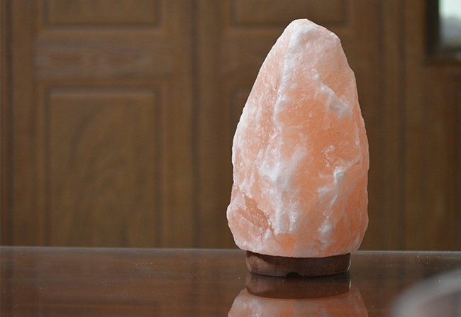 Natural shape USB lamp pink salt with rugged crystalline facets mounted on a round dark wooden base