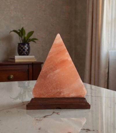 Handcrafted pyramid shape table lamp with smooth angled facets carved from Himalayan pink salt mounted on a stepped wooden base