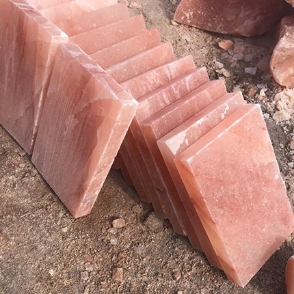 Row of handcrafted rectangular Himalayan pink salt cooking tiles and grilling slabs leaning in a line