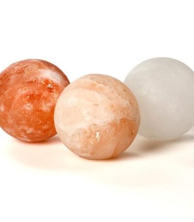Three handcrafted smooth round Himalayan pink salt massage balls in red, peach, and white crystal shades.