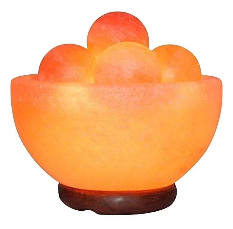 Handcrafted pink salt bowl with round balls and polished wooden base filled with smooth salt massage spheres