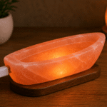 Handcrafted illuminated USB boat salt lamp carved from Himalayan pink salt mounted on a dark elongated wooden base