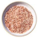 Medium granules of pure Himalayan pink salt displayed neatly in a round decorative ceramic plate