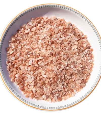 Medium granules of pure Himalayan pink salt displayed neatly in a round decorative ceramic plate