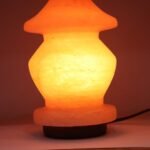 Handcrafted illuminated pagoda shape Himalayan pink salt lamp with tiered contours mounted on a dark wooden base