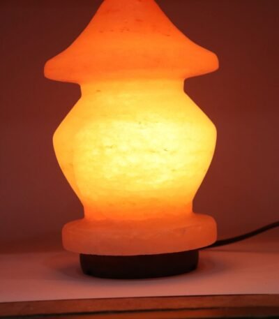 Handcrafted illuminated pagoda shape Himalayan pink salt lamp with tiered contours mounted on a dark wooden base