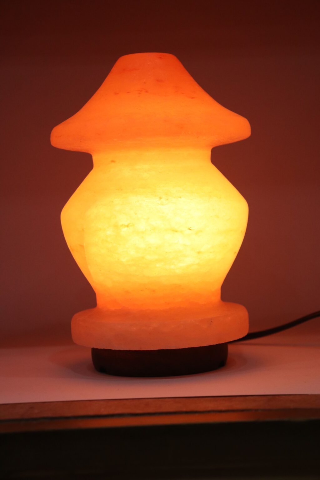 Pagoda Shape Himalayan Pink Salt Lamp - Ambient Decor Handcrafted illuminated pagoda shape Himalayan pink salt lamp with tiered contours mounted on a dark wooden base