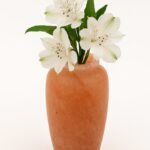 Handcrafted Himalayan pink salt flower vase holding white flowers on a clean white background