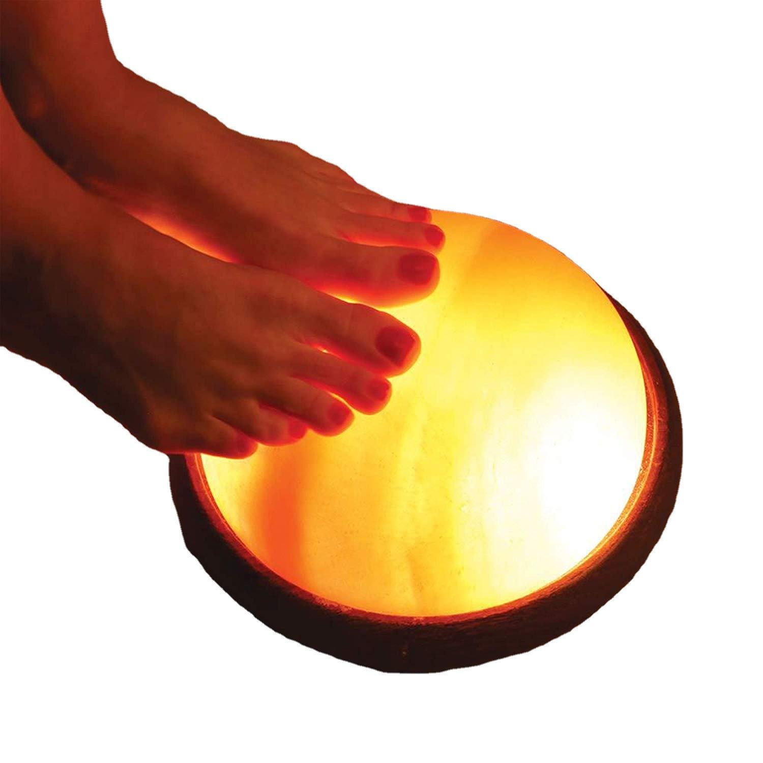 Himalayan Pink Salt Foot Detox Dome Lamp - Spa Wellness Decor Bare feet resting on an illuminated handcrafted Himalayan pink salt foot detox dome lamp mounted on a dark round wooden base