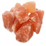 Mound of natural rough Himalayan pink rock salt chunks with crystalline facets on a pure white background